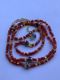 a red and gold beaded necklace on a white surface