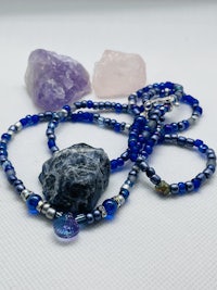 a necklace with blue beads and crystals on a white table