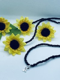 a necklace with sunflowers and a silver charm