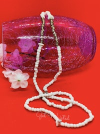 a white beaded necklace with a pink vase